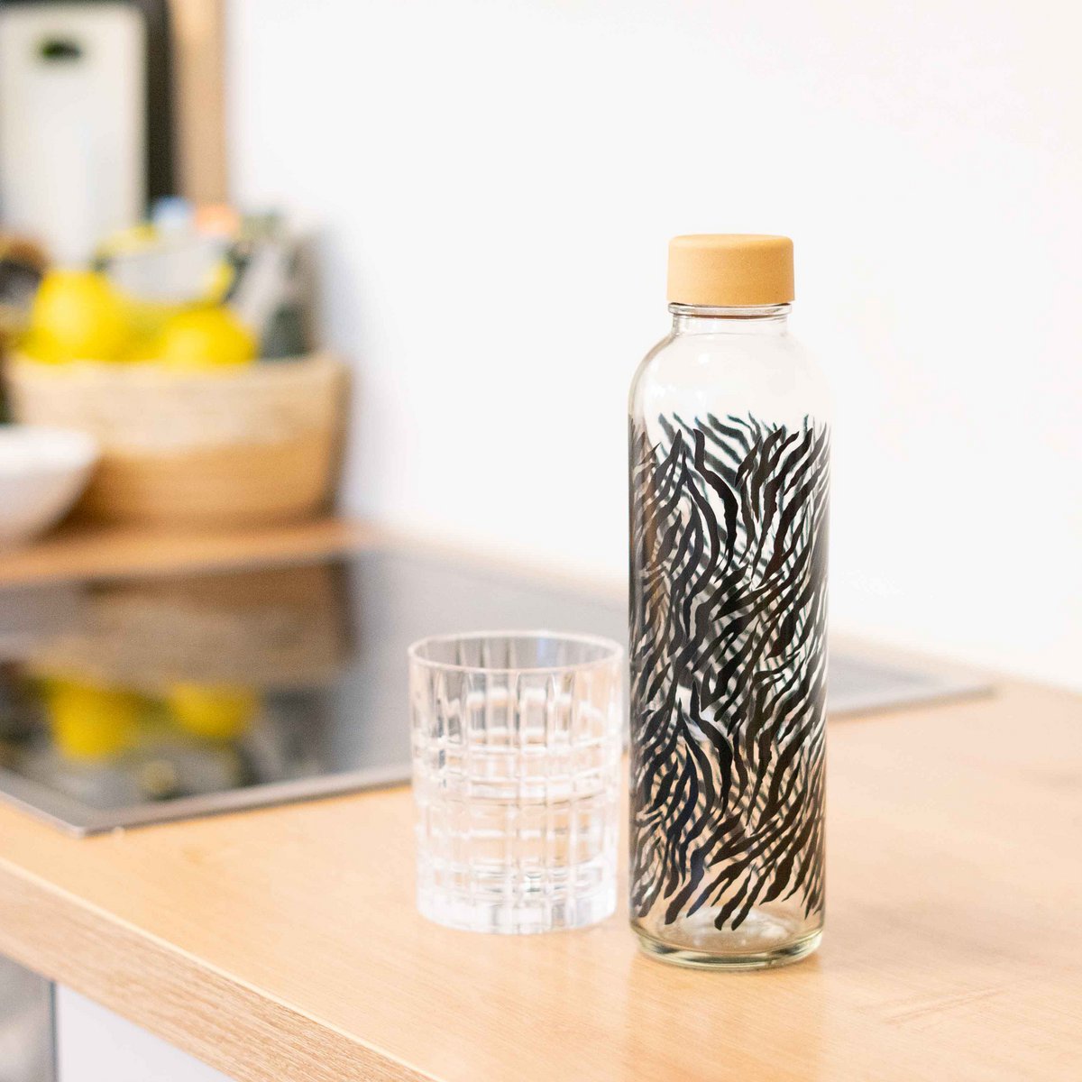 Nachhaltige CARRY Glasflaschen und Schutzhüllen aus recyceltem Glas und PET-Filz, fotografiert auf hellem Naturuntergrund, Made in Germany.